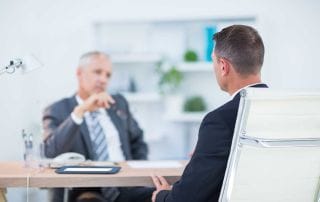 Two businessmen sitting and speaking at the office about psychosocial hazards